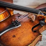 Two Fiddles On A Wooden Background