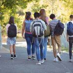 Rear view of school kids walking on road in campus at school