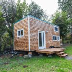 Portable Tiny Home With Wood Siding In The Back Yard Of A Larger